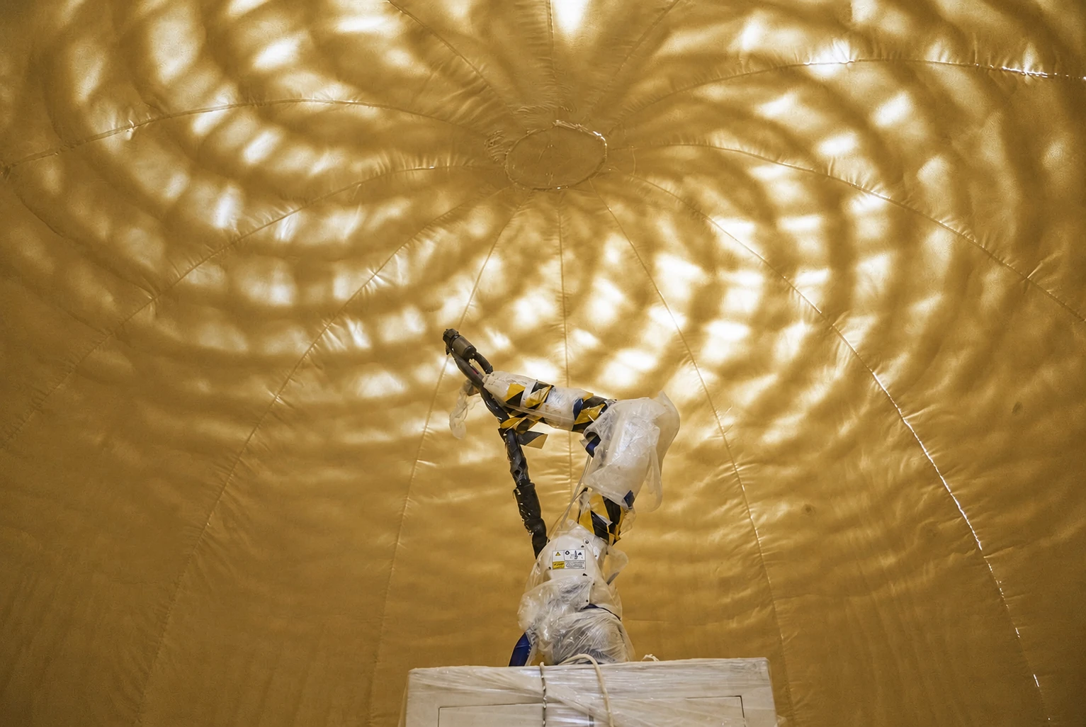 A compact robot spraying polyurethane inside an inflated architectural enclosure