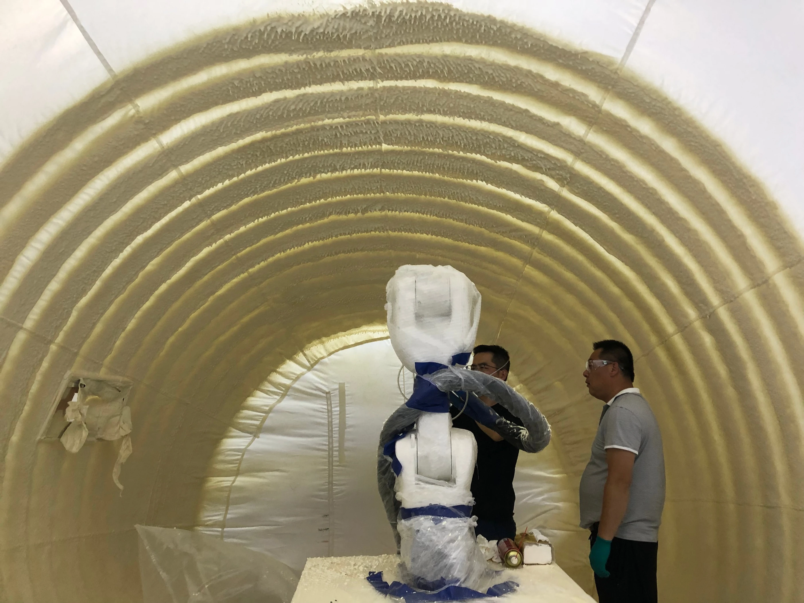 Robot and researchers inside the five-metre prototype inspecting polyurethane bands during curing