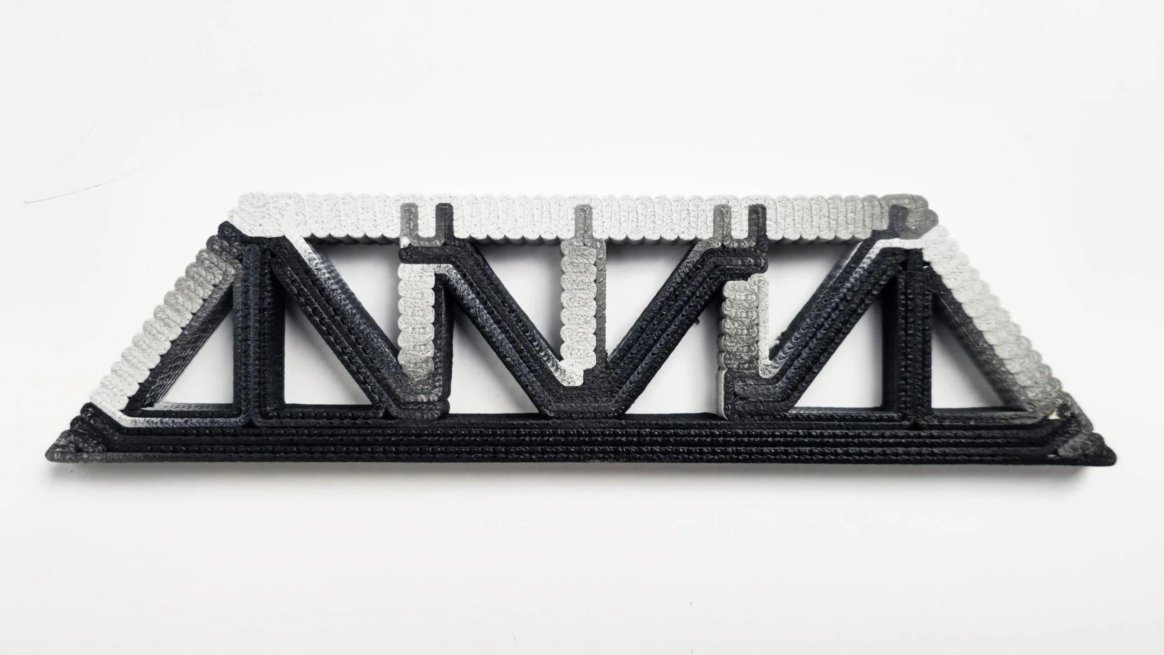 Printed truss with distinct materials along tension and compression regions