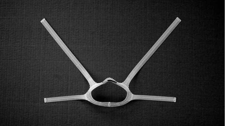 Flat 3D-printed fabric-fitter frame with flexible patterned arms before forming around the face