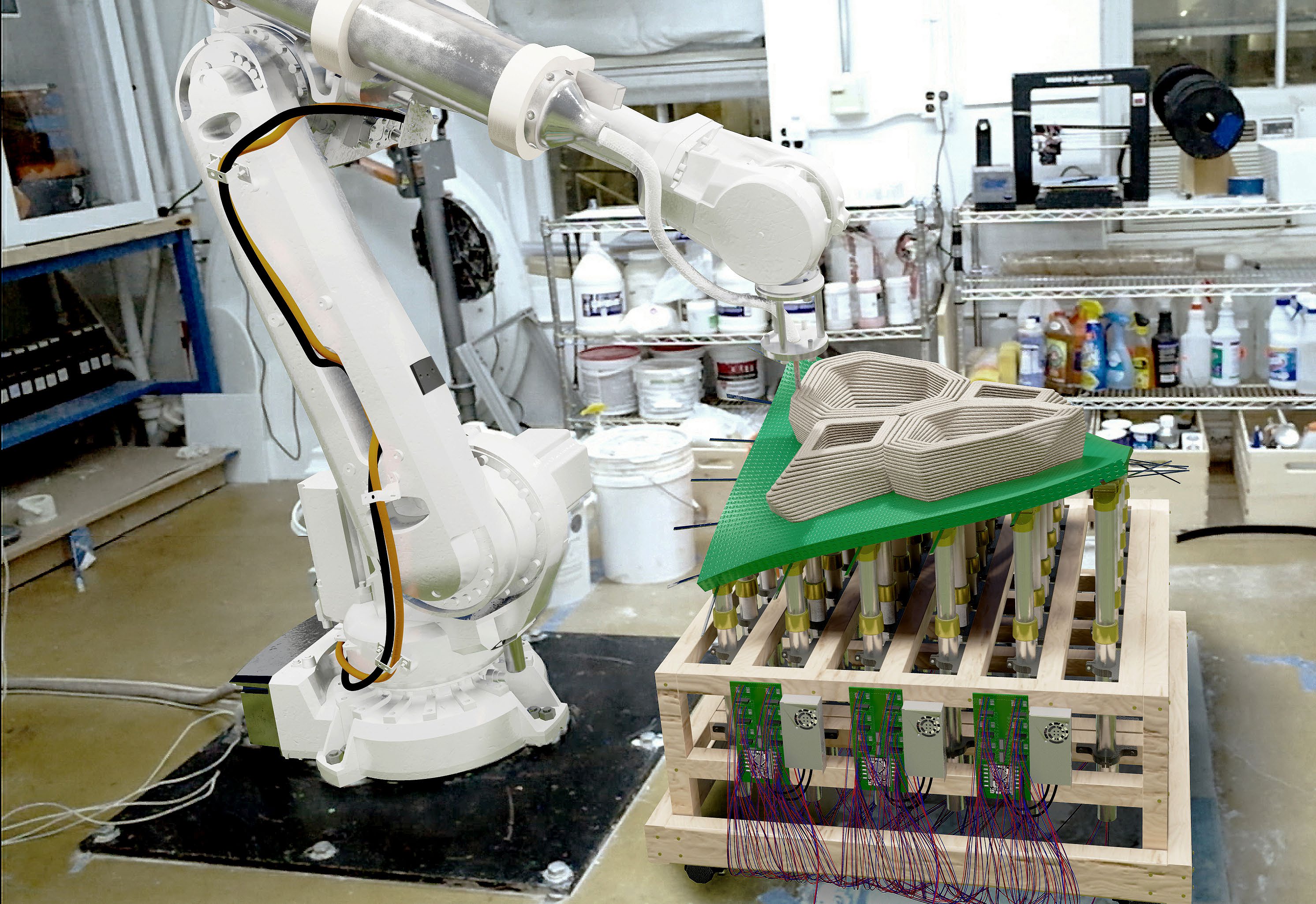 Pinbed prototype beside the robotic arm, supporting an initial printed component