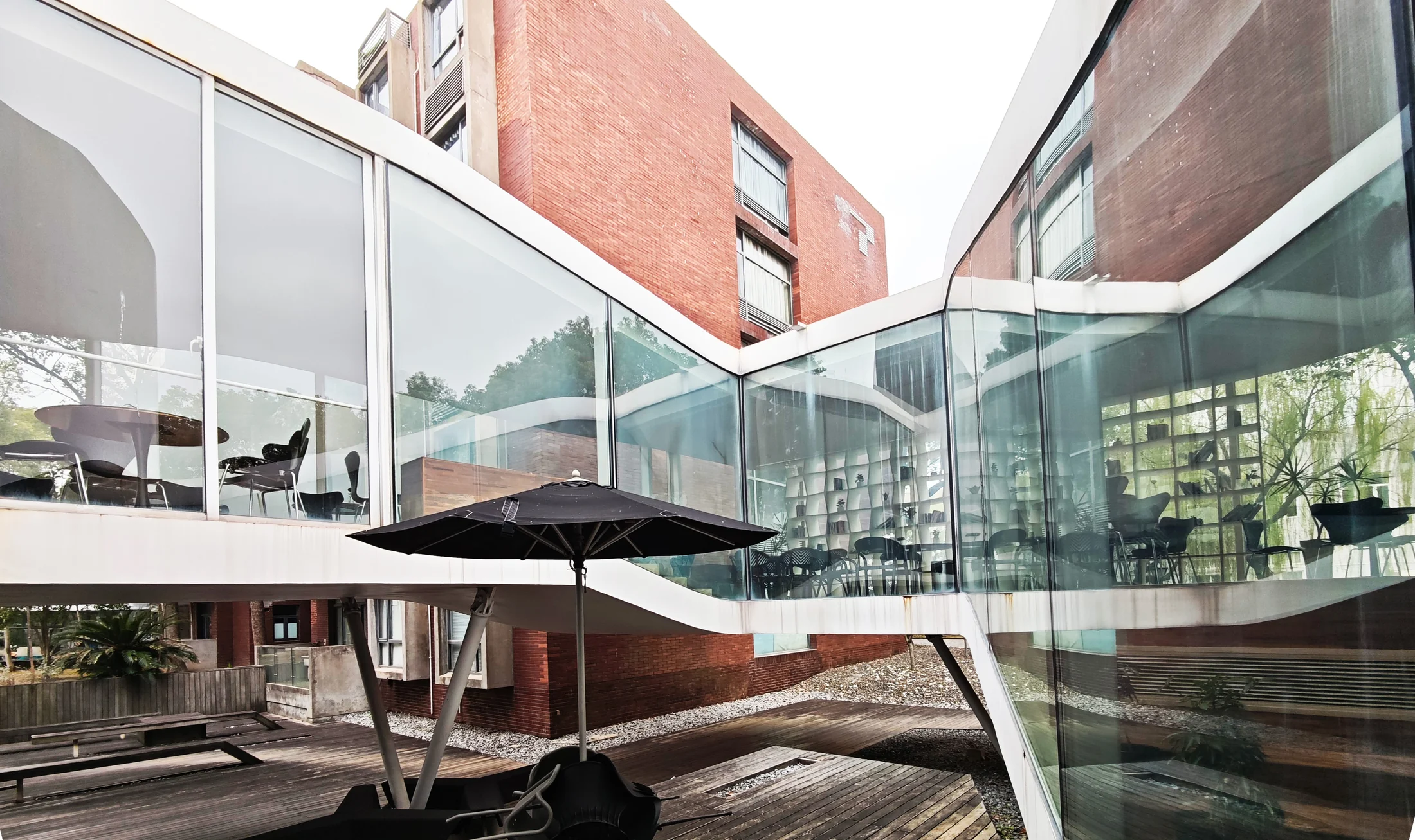 The courtyard terrace sits between the glazed interior and the existing campus buildings.