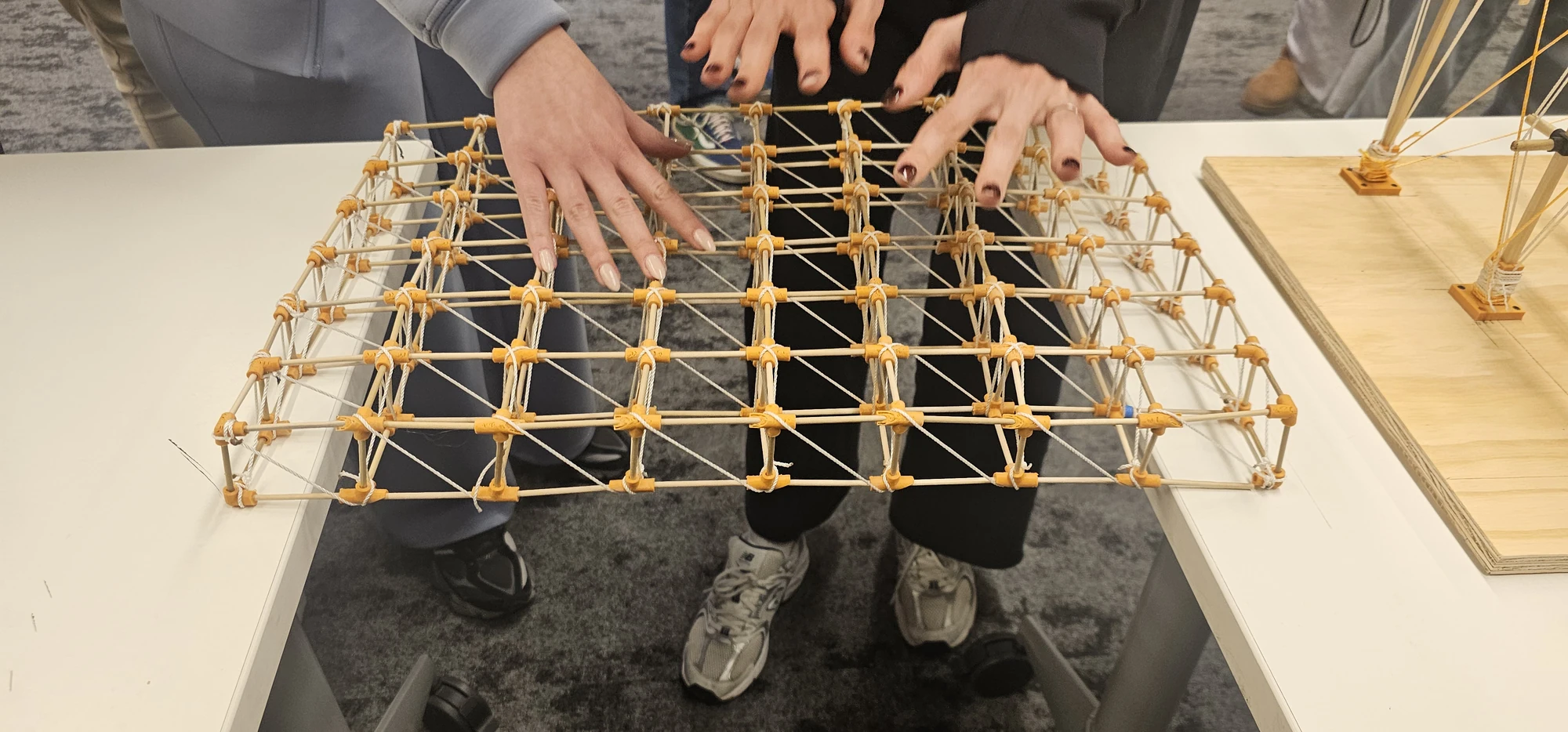 Lucas Guldner, Nick Henderson, Dylan Ries, and Gretchen Ullrich — hands applying load to the space-truss roof during review