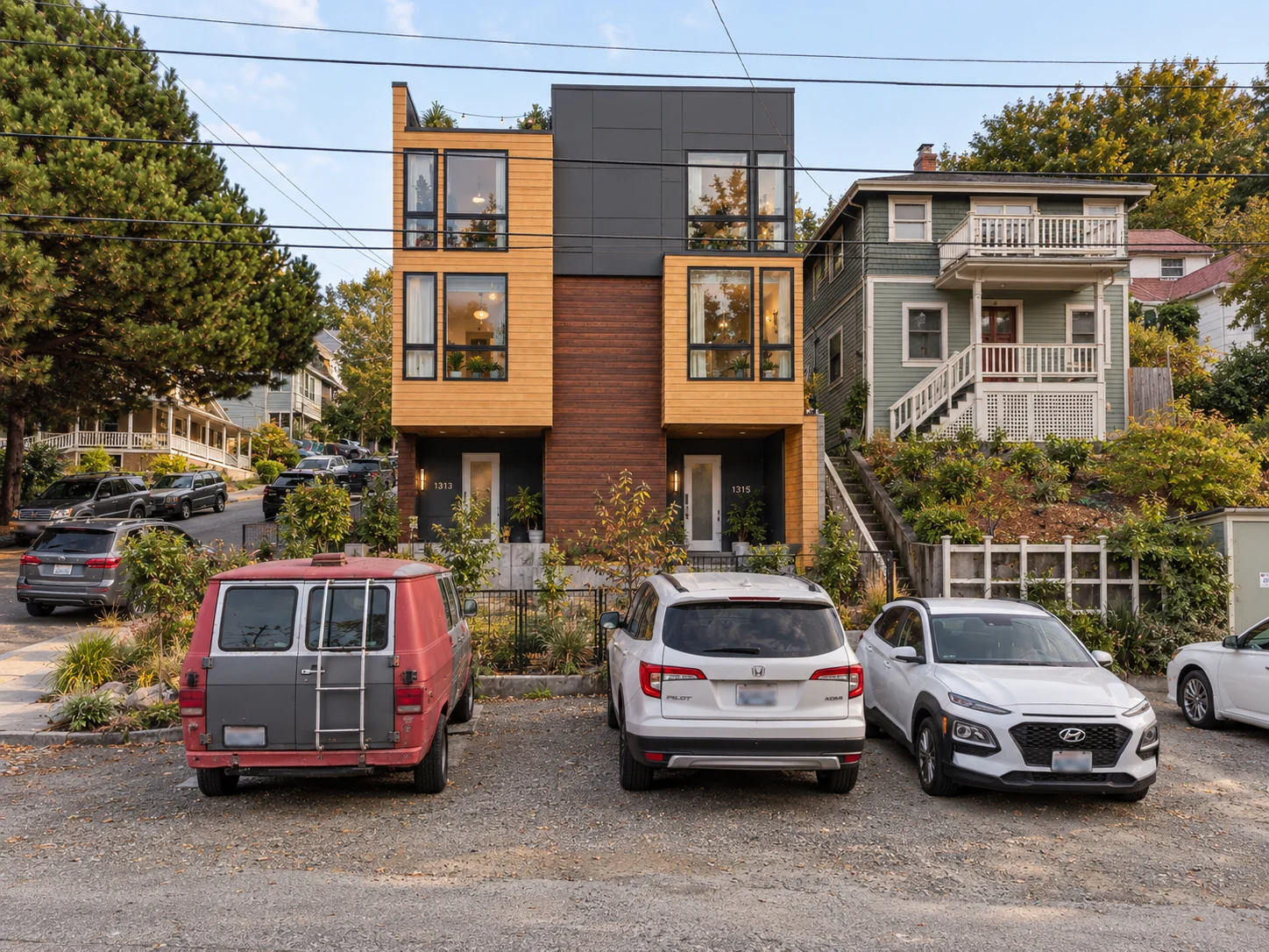 The uphill elevation combines recessed entrances, brick, and framed window bays.